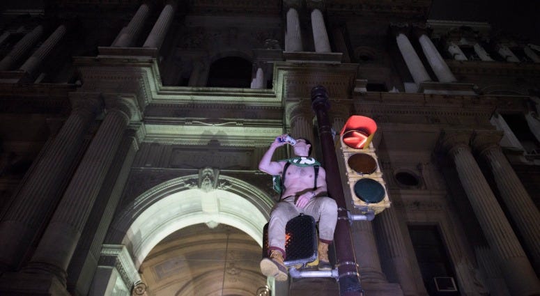 A Philadelphia Eagles fan drinks a beer atop a traffic light post outside City Hall as fans celebrate along Broad Street in Philadelphia following a Super Bowl win against the New England Patriots, Feb. 5, 2018. Eagles fan
