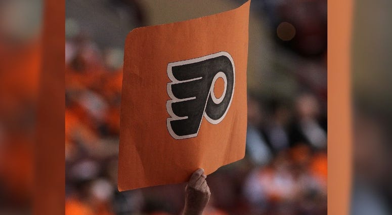 A hockey fan holds up a Flyers logo A hockey fan holds up a Flyers logo