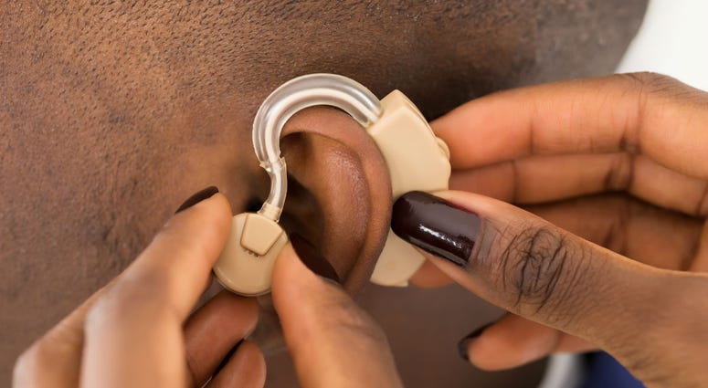 A man is fitted for a hearing aid A man is fitted for a hearing aid
