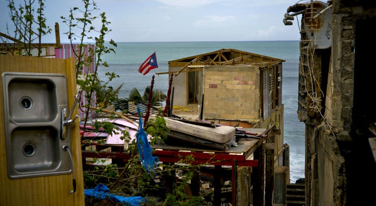 In this Oct. 5, 2017 file photo, a Puerto Rican national flag is mounted on debris of a damaged home in the aftermath of Hurricane Maria in the seaside slum La Perla, San Juan, Puerto Rico. In this Oct. 5, 2017 file photo, a Puerto Rican national flag is mounted on debris of a damaged home in the aftermath of Hurricane Maria in the seaside slum La Perla, San Juan, Puerto Rico.