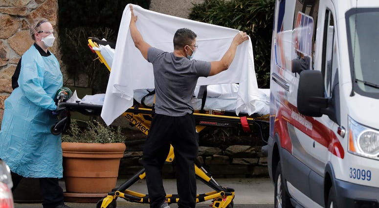 A staff member blocks the view as a person is taken by a stretcher to a waiting ambulance from a nursing facility where dozens of people are being tested for Wuhan coronavirus. A staff member blocks the view as a person is taken by a stretcher to a waiting ambulance from a nursing facility where dozens of people are being tested for Wuhan coronavirus.