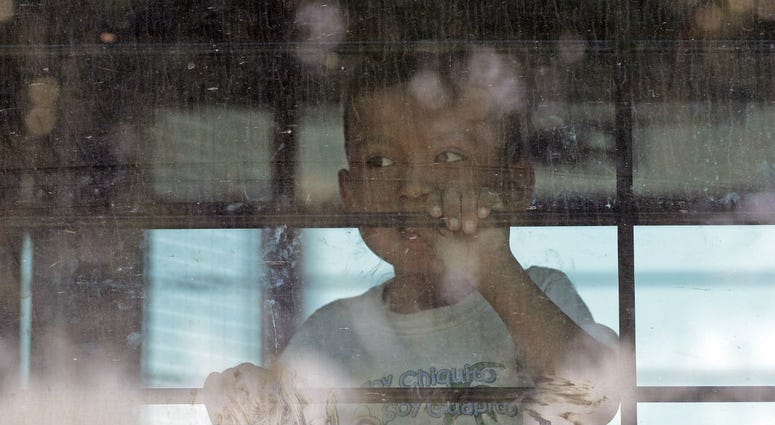 In this June 23, 2018, file photo, an immigrant child looks out from a U.S. Border Patrol bus leaving as protesters block the street outside the U.S. Border Patrol Central Processing Center in McAllen, Texas. In this June 23, 2018, file photo, an immigrant child looks out from a U.S. Border Patrol bus leaving as protesters block the street outside the U.S. Border Patrol Central Processing Center in McAllen, Texas.