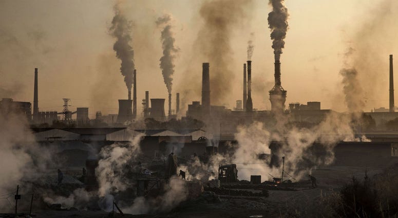 Smoke billows from a large steel plant as a Chinese labourer works at an unauthorized steel factory, foreground, on November 4, 2016, in Inner Mongolia, China. Pollution