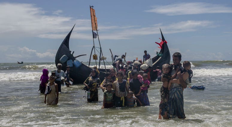 In this Sept. 14, 2017 file photo, a Rohingya man carries two children to shore in Shah Porir Dwip, Bangladesh, after they arrived on a boat from Myanmar. In this Sept. 14, 2017 file photo, a Rohingya man carries two children to shore in Shah Porir Dwip, Bangladesh, after they arrived on a boat from Myanmar.