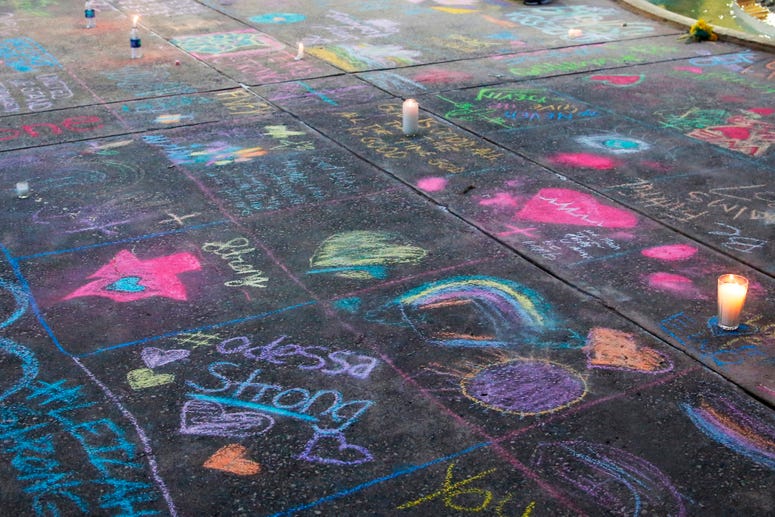 A sidewalk is filled with chalk messages following a prayer service, Sunday, Sept. 1, 2019, in Odessa, Texas, for the victims of a shooting spree the day before. Vigil for Odessa, Texas shooting