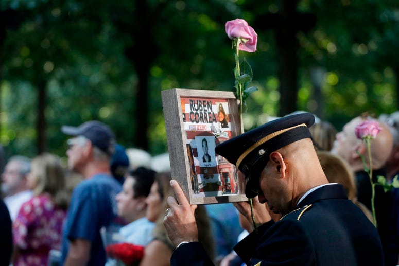 A man holds a photo of a victim during a ceremony marking the 18th anniversary of the attacks of Sept. 11, 2001, at the National September 11 Memorial, Wednesday, Sept. 11, 2019, in New York. Anniversary of 9/11