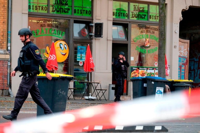 A police officer walks in front of a kebab grill in Halle, Germany, Wednesday, Oct. 9, 2019. A gunman fired several shots on Wednesday in the German city of Halle. Police say a person has been arrested after a shooting that left two people dead. A police officer walks in front of a kebab grill in Halle, Germany.