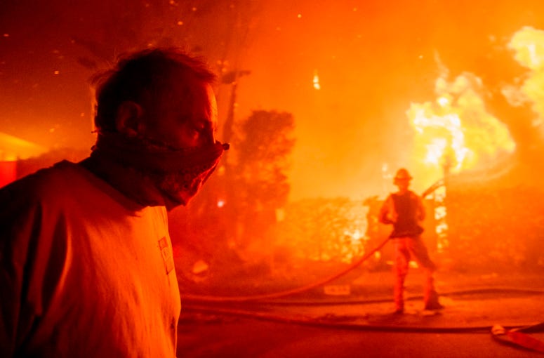 A man walks past a burning home during the Getty fire, Monday, Oct. 28, 2019, in Los Angeles, Calif. California wildfires