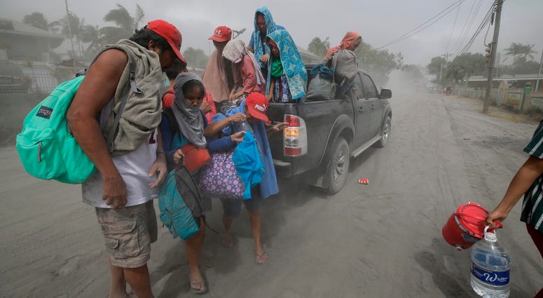 A family evacuates to safer grounds as Taal volcano in Tagaytay, Cavite province, southern Philippines on Monday, Jan. 13, 2020. Aftermath of Philippines volcanic eruption