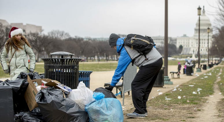 The Capitol building is visible as a man who declined to give his name picks up garbage and stacks it near a trash can during a partial government shutdown on the National Mall in Washington, Tuesday, Dec. 25, 2018. The Capitol building is visible as a man who declined to give his name picks up garbage and stacks it near a trash can during a partial government shutdown on the National Mall in Washington, Tuesday, Dec. 25, 2018.