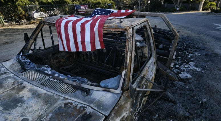 An American flag is draped over the charred remains of an old pickup truck entering Point Dume along the pacific coast highway in Malibu, Calif., on Sunday Nov. 11, 2018. An American flag is draped over the charred remains of an old pickup truck entering Point Dume along the pacific coast highway in Malibu, Calif., on Sunday Nov. 11, 2018.