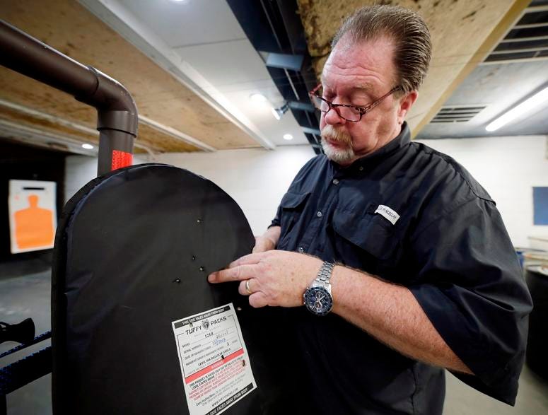 Steve Naremore, founder and CEO of TuffyPacks, shows the impact points on a ballistic shield retrieved from a backpack after a shooting demonstration of the stopping ability of the product at the Shiloh Shooting Range, Friday, August 9, 2019, in Houston. Bullet-resistant backpacks