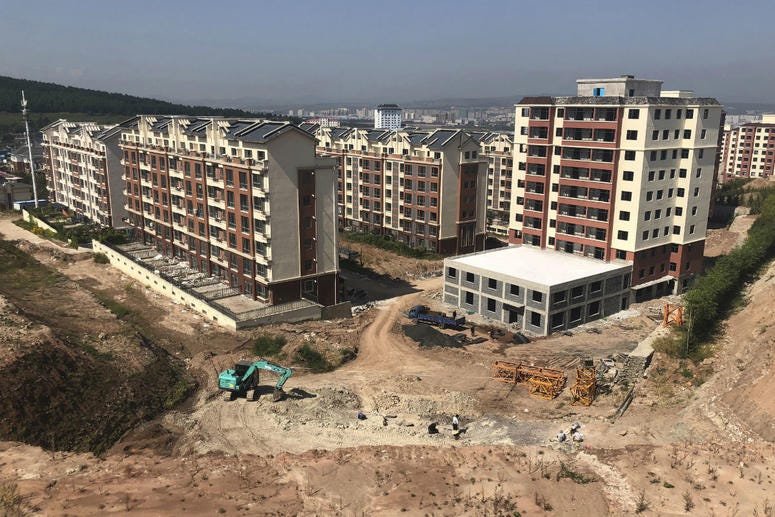 In this Sept. 12, 2018, photo, paleontologist Xu Xing leads a dig site, foreground, next to new apartments being constructed in Yanji, China. In this Sept. 12, 2018, photo, paleontologist Xu Xing leads a dig site, foreground, next to new apartments being constructed in Yanji, China.