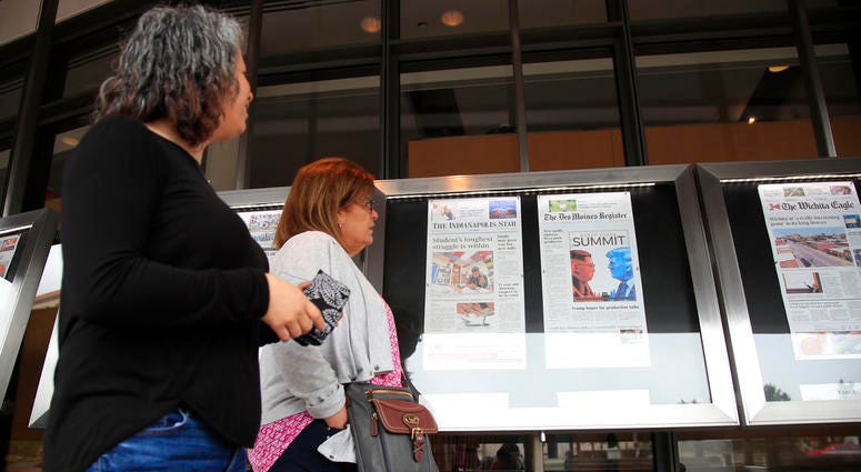 Newseum visitors browse newspaper front pages displayed outside the museum in Washington. Newseum visitors browse newspaper front pages displayed outside the museum in Washington.