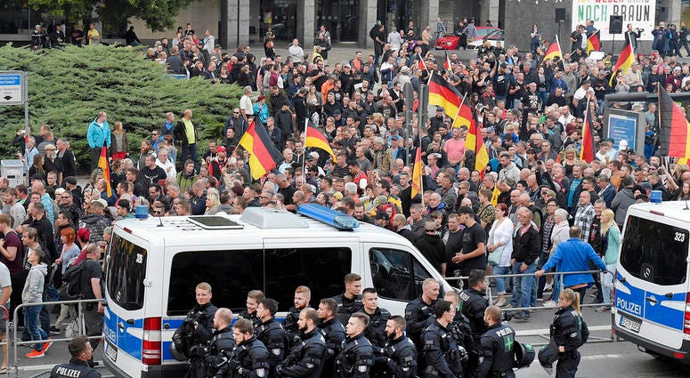 People are watched by police as they attend a demonstration in eastern Germany, Sept. 7, 2018, after several nationalist groups called for marches protesting the killing of a German man two weeks ago, allegedly by migrants from Syria and Iraq. People are watched by police as they attend a demonstration in eastern Germany, Sept. 7, 2018, after several nationalist groups called for marches protesting the killing of a German man two weeks ago, allegedly by migrants from Syria and Iraq.
