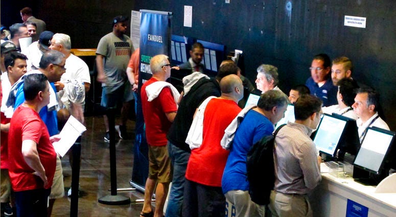 In this July 14, 2018, photo gamblers place bets on sports events at the FanDuel sports book at the Meadowlands Racetrack in East Rutherford N.J. FanDuel agreed to pay a gambler $82,000 for a payout its computers wrongly promised him on the outcome of a f