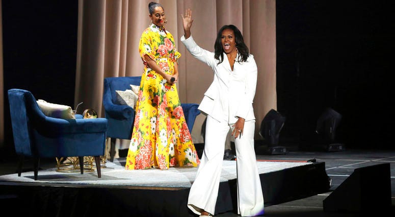 Former first lady Michelle Obama greets the audience as Tracee Ellis Ross watches at the "Becoming: An Intimate Conversation with Michelle Obama" event at the Forum on Thursday, Nov. 15, 2018, in Inglewood, Calif. Former first lady Michelle Obama greets the audience as Tracee Ellis Ross watches at the "Becoming: An Intimate Conversation with Michelle Obama" event at the Forum on Thursday, Nov. 15, 2018, in Inglewood, Calif.