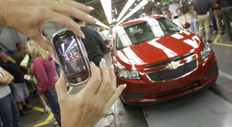 FILE - In this Sept. 8, 2010 file photo, auto worker Brenda Hedland takes a picture of the first Chevrolet Cruze compact sedan to come off the assembly line at a ceremony inside the GM factory in Lordstown, Ohio. FILE - In this Sept. 8, 2010 file photo, auto worker Brenda Hedland takes a picture of the first Chevrolet Cruze compact sedan to come off the assembly line at a ceremony inside the GM factory in Lordstown, Ohio.