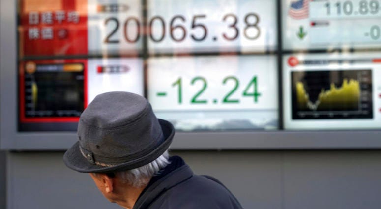 A man walks past an electronic stock board showing Japan's Nikkei 225 index at a securities firm in Tokyo Friday, Dec. 28, 2018. A man walks past an electronic stock board.