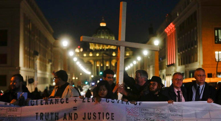 Survivors of sex abuse hold a cross as they gather in front of Via della Conciliazione, the road leading to St. Peter's Square, visible in background, during a twilight vigil prayer of the victims of sex abuse, in Rome, Thursday, Feb. 21, 2019. Survivors of sex abuse hold a cross as they gather in front of Via della Conciliazione, the road leading to St. Peter's Square, visible in background, during a twilight vigil prayer of the victims of sex abuse, in Rome, Thursday, Feb. 21, 2019.