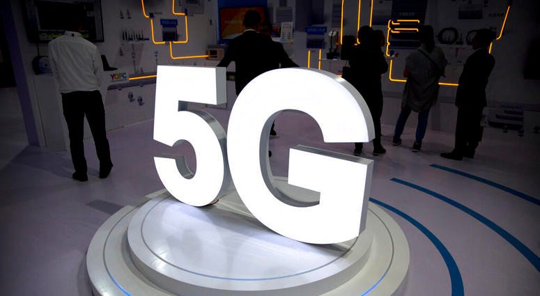 In this Sept. 26, 2018, file photo visitors stand near a 5G logo at a display the PT Expo in Beijing. Visitors stand near a 5G logo at a display the PT Expo in Beijing.