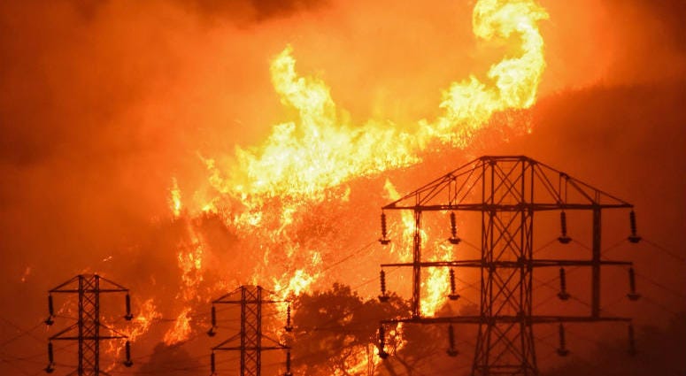 FILE - In this Dec. 16, 2017, file photo provided by the Santa Barbara County Fire Department, flames burn near power lines in Sycamore Canyon near West Mountain Drive in Montecito, Calif. FILE - In this Dec. 16, 2017, file photo provided by the Santa Barbara County Fire Department, flames burn near power lines in Sycamore Canyon near West Mountain Drive in Montecito, Calif.
