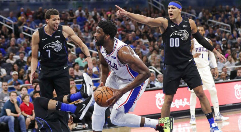 Philadelphia 76ers' Joel Embiid, center, is called for a charge as he runs into Orlando Magic's Khem Birch, lower left, as Magic's Michael Carter-Williams (7) and Aaron Gordon (00) look on during the first half of an NBA basketball game, Monday, March 25, Philadelphia 76ers' Joel Embiid, center, is called for a charge as he runs into Orlando Magic's Khem Birch, lower left, as Magic's Michael Carter-Williams (7) and Aaron Gordon (00) look on during the first half of an NBA basketball game.