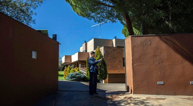 In this Wednesday, March 13, 2019 photo, a member of the North Korea's embassy tells reporters not to take pictures of the diplomatic building in Madrid, Spain. A Spanish court is accusing an American, Mexican and South Korean part of a 10-strong group that led an attack on the North Korean Embassy in February, saying the FBI was offered stolen data.