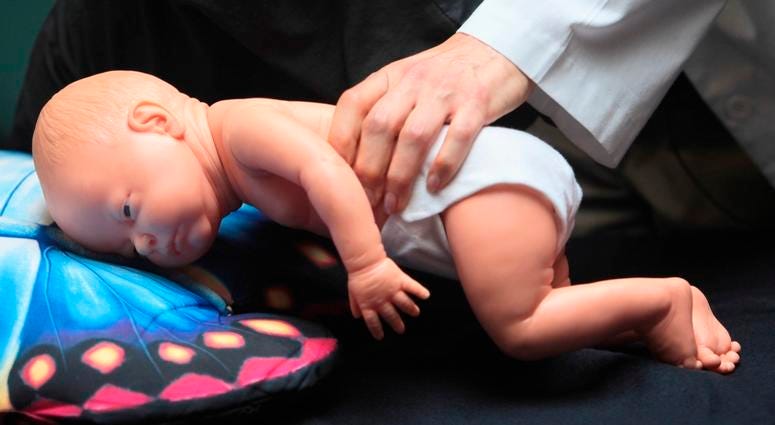 In this March 22, 2012 file photo, a doctor demonstrates how an infant can die due to unsafe sleeping practices using a scene re-enactment doll in Norfolk, Va. A doctor demonstrates how an infant can die due to unsafe sleeping practices.