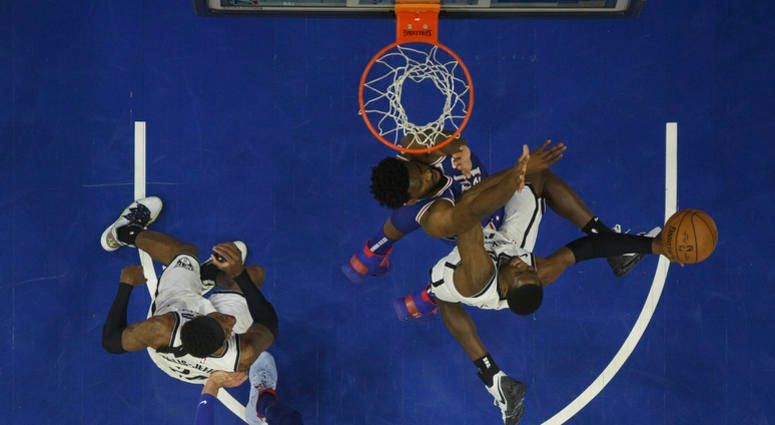 Brooklyn Nets' Caris LeVert, right, goes up for the shot against Philadelphia 76ers' Joel Embiid, center right, of Cameroon, during the first half in Game 5 of a first-round NBA basketball playoff series, Tuesday, April 23, 2019, in Philadelphia. Brooklyn Nets against Philadelphia 76ers