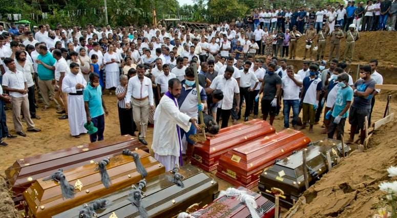 A priest conducts religious rituals during a mass burial for Easter Sunday bomb blast victims in Negombo, Sri Lanka, Wednesday, April 24, 2019. A mass burial for victims in Sri Lanka.