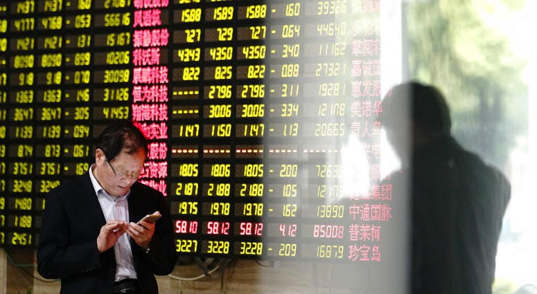 A man looks at his smartphone near a display showing stock prices at a brokerage house in Shanghai Monday, May 6, 2019. A man looks at his smartphone near a display showing stock prices at a brokerage house in Shanghai Monday, May 6, 2019.