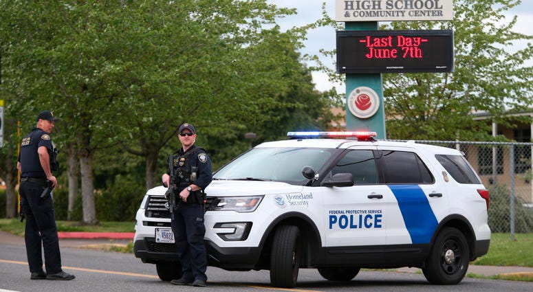 Police are positioned outside Parkrose High School during a lockdown after a man armed with a gun was wrestled to the ground by a staff member, Friday, May 17, 2019 in Portland, Ore. Police outside Parkrose High School
