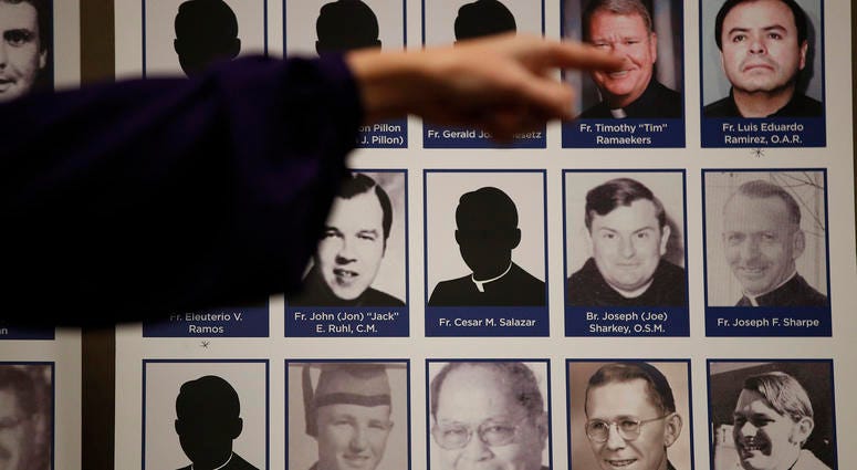 In this Thursday, Dec. 6, 2018 file photo, a sexual abuse victim points to the photos of Catholic priests accused of sexual misconduct by victims during a news conference in Orange, Calif. Victim points to photos of Catholic priests accused of sexual misconduct.