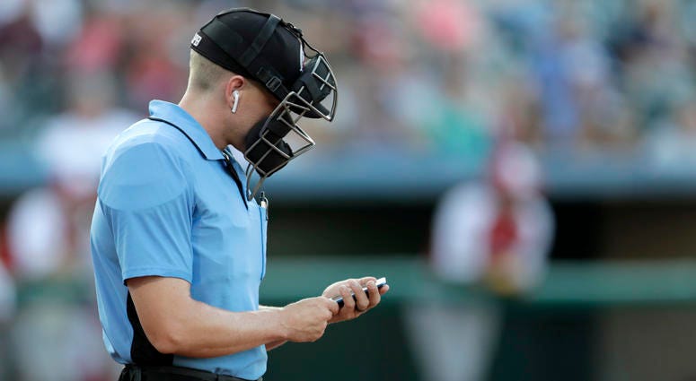 Home plate umpire Brian deBrauwere checks an iPhone while wearing an earpiece prior to the start of the Atlantic League All-Star minor league baseball game, Wednesday, July 10, 2019, in York, Pa. Umpire