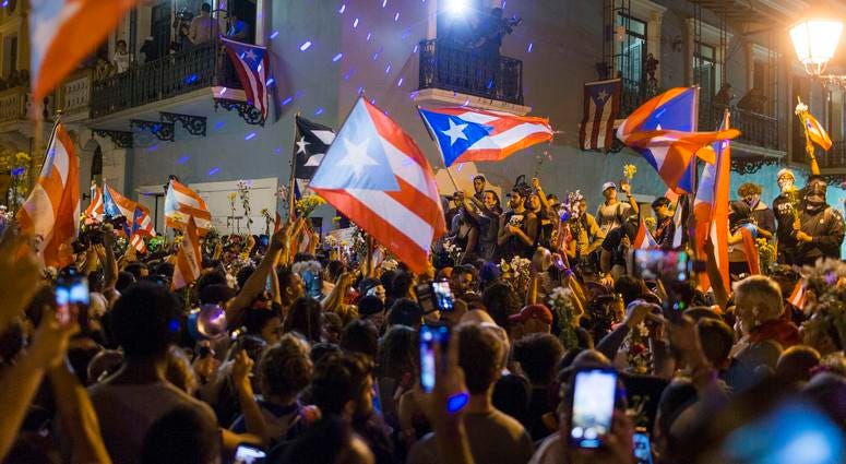 People celebrate outside the governor's mansion La Fortaleza, after Gov. Ricardo Rossello announced that he is resigning Aug. 2 after nearly two weeks of protests, in San Juan, Puerto Rico, July 25, 2019. Puerto Rico protests