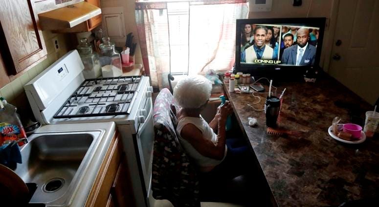 Carrie Newson watches television in the dining area inside her home at the Dutch Village apartments, Tuesday, July 30, 2019, in Baltimore. Dutch Village apartments