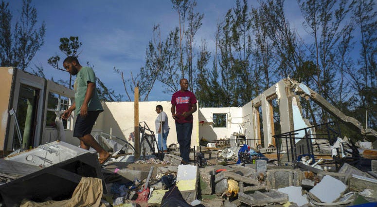 George Bolter, left, and his parents walk through the remains of his home destroyed by Hurricane Dorian in the Pine Bay neighborhood of Freeport, Bahamas, Wednesday, Sept. 4, 2019. People walk through the remains of a home in the Bahamas.