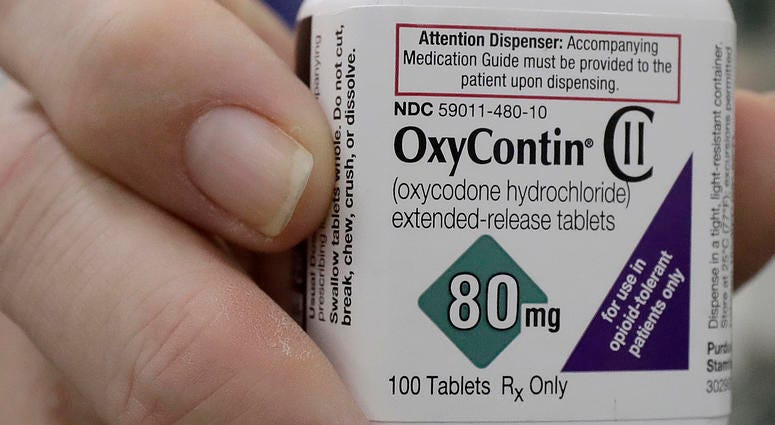 In this April 2, 2018, file photo, a pharmacist in San Francisco poses for photos holding a bottle of OxyContin. OxyContin