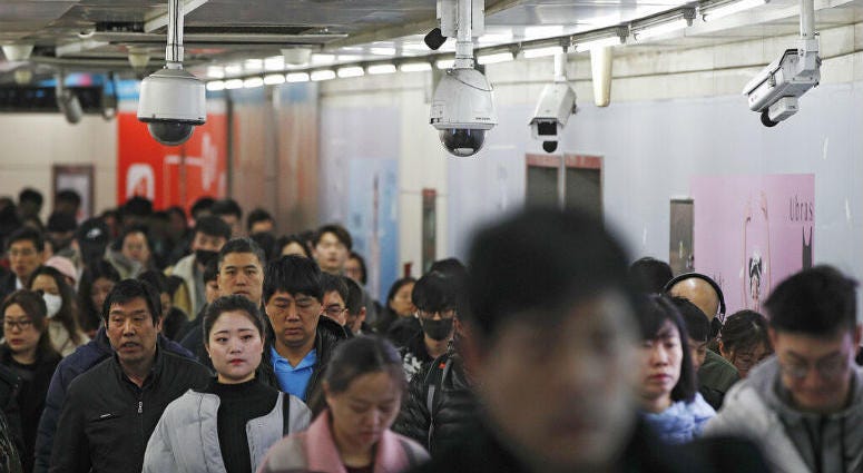 FILE - In this Feb. 26, 2019, file photo commuters walk by surveillance cameras installed at a walkway in between two subway stations in Beijing. Commuters walk by surveillance cameras installed at a walkway in between two subway stations in Beijing.