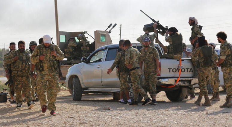State-run Anadolu news agency reported Tal Abyad had fallen to a Turkish military offensive on Sunday. Turkish-backed Syrian opposition fighters on pick-up trucks celebrate as they drive in Tal Abyad, Syria, Sunday, Oct. 13, 2019.