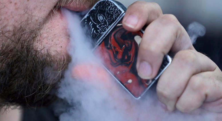 In this Friday, Oct. 4, 2019 photo, a man using an electronic cigarette exhales in Mayfield Heights, Ohio. Vaping-related illnesses in the U.S. are still rising, though at a slightly slower pace.