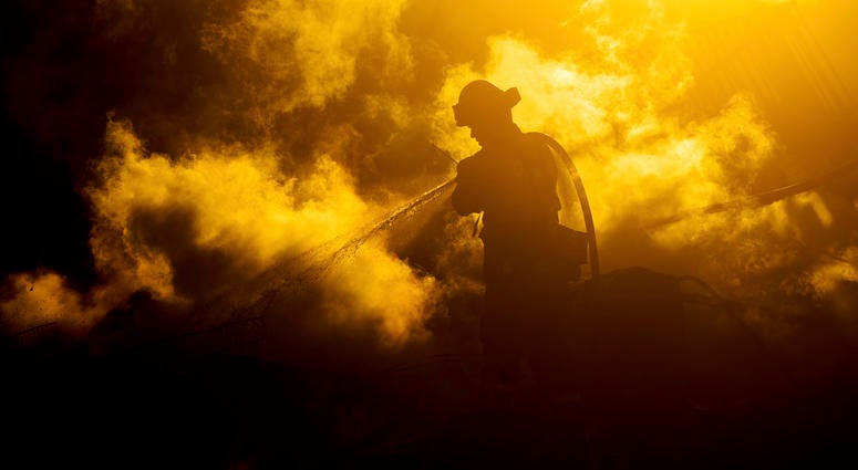 A firefighter sprays water on a leveled home as the Hillside Fire burns in San Bernardino, Calif., on Thursday, Oct. 31, 2019. Whipped by strong wind, the blaze destroyed multiple residences. California wildfires