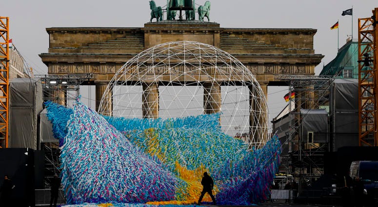The skynet artwork 'Visions In Motion' is set to overhang the 'Strasse des 17. Juni' (Street of June 17) boulevard in front of the Brandenburg Gate in Berlin, Germany, Friday, Nov. 1, 2019. The skynet artwork 'Visions In Motion' is set to overhang the 'Strasse des 17. Juni' (Street of June 17) boulevard in front of the Brandenburg Gate in Berlin, Germany, Friday, Nov. 1, 2019.