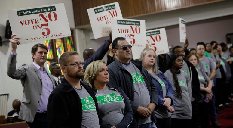In this Sunday, Nov. 3, 2019, photo, people wearing "Save The Paseo" shirts stand among attendees at a rally to keep a street named in honor of Dr. Martin Luther King Jr. at Paseo Baptist Church in Kansas City, Mo. Save The Paseo protesters