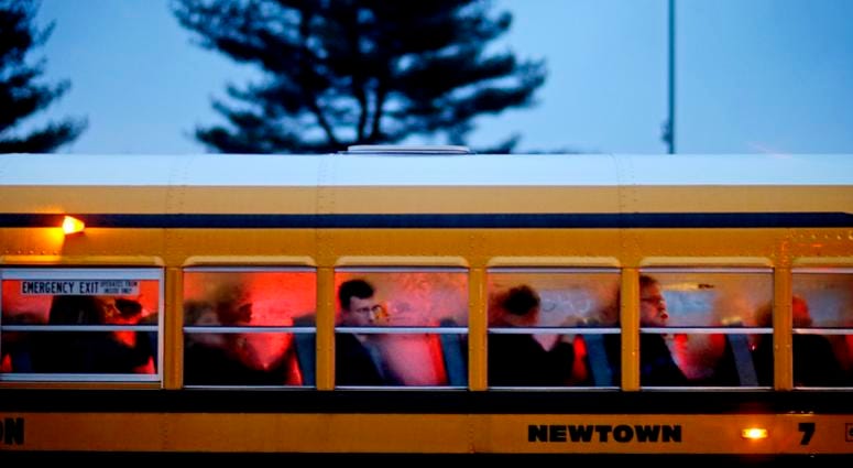 In this Dec. 16, 2012 file photo, people arrive on a school bus at Newtown High School for a memorial vigil attended by President Barack Obama for the victims of the Sandy Hook Elementary School shooting, in Newtown, Conn. Newtown High School