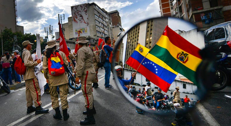 Reflected in a motorcycle side mirror, supporters of Venezuelan President Nicolas Maduro rally in support of former Bolivian President Evo Morales in Caracas, Venezuela, Monday, Nov. 11, 2019. Reflected in a motorcycle side mirror, supporters of Venezuelan President Nicolas Maduro rally in support of former Bolivian President Evo Morales in Caracas, Venezuela, Monday, Nov. 11, 2019.