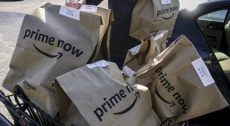 In this Feb. 8, 2018, file photo, Amazon Prime Now bags full of groceries are loaded for delivery by a part-time worker outside a Whole Foods store in Cincinnati. In this Feb. 8, 2018, file photo, Amazon Prime Now bags full of groceries are loaded for delivery by a part-time worker outside a Whole Foods store in Cincinnati.