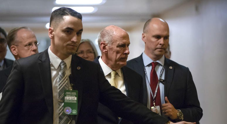 National Intelligence Director Dan Coats, center, is surrounded by security as he departs the Capitol after House and Senate lawmakers from both parties met for a classified briefing about the federal investigation into President Trump's 2016 campaign. National Intelligence Director Dan Coats