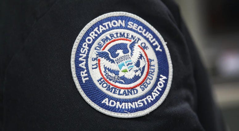 A patch is seen on the jacket of a Transportation Security Administration official as he works at the automated screening lanes funded by American Airlines. TSA